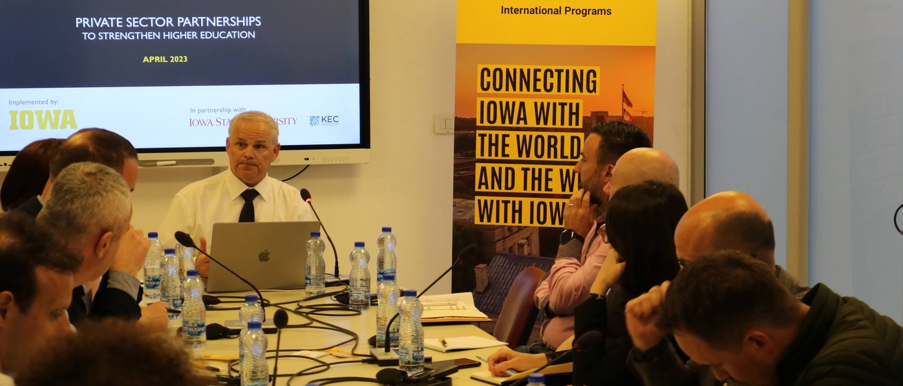 College of Education Dean Daniel L. Clay sits at the head of a conference table, leading a workshop with industry experts in Kosovo.
