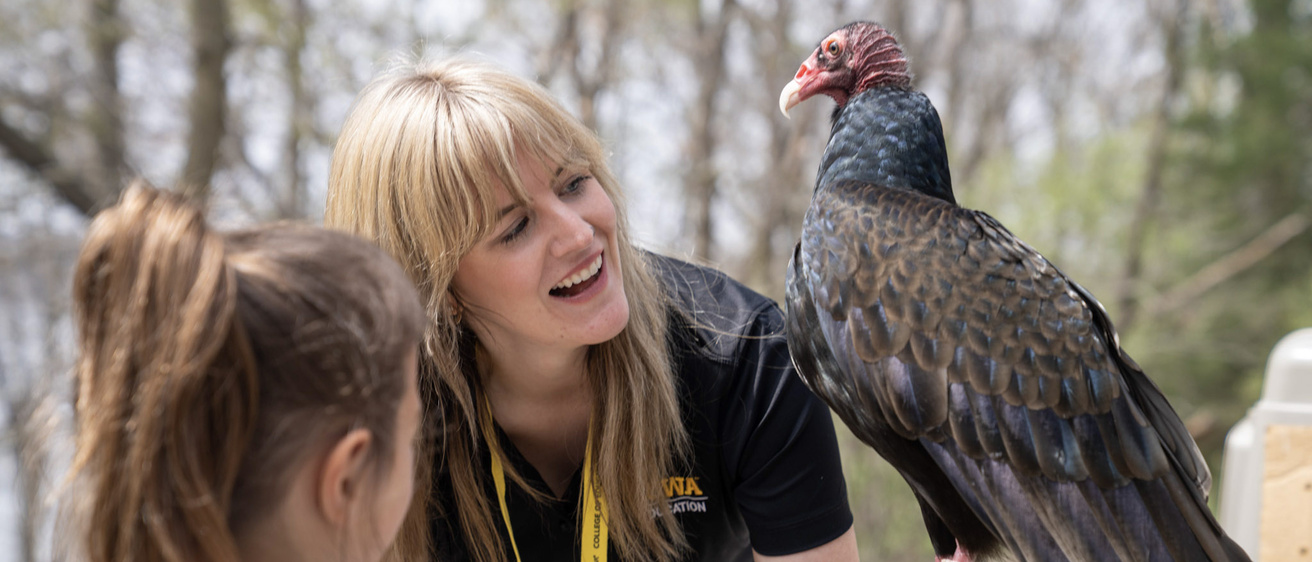 Woman smiles while holding raptor and showing little girl
