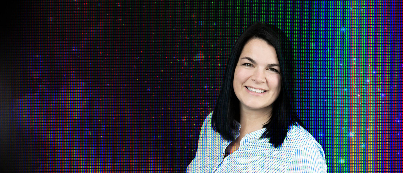 Woman smiles in a field of abstract rainbows
