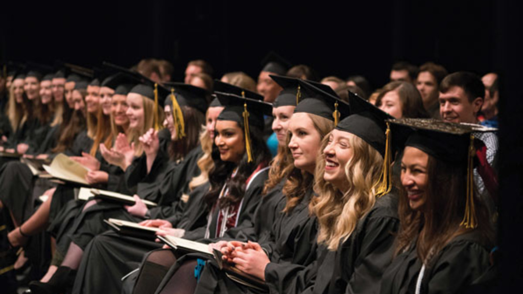 Students sitting and smiling during commencement. 