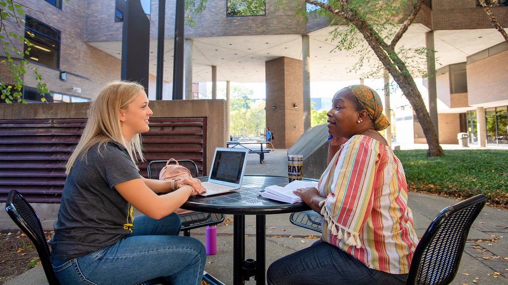 Two students working outside the education building