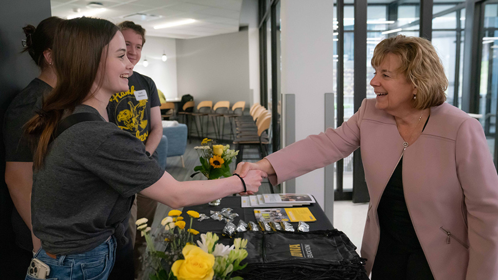 UI President Wilson shakes hands with a student