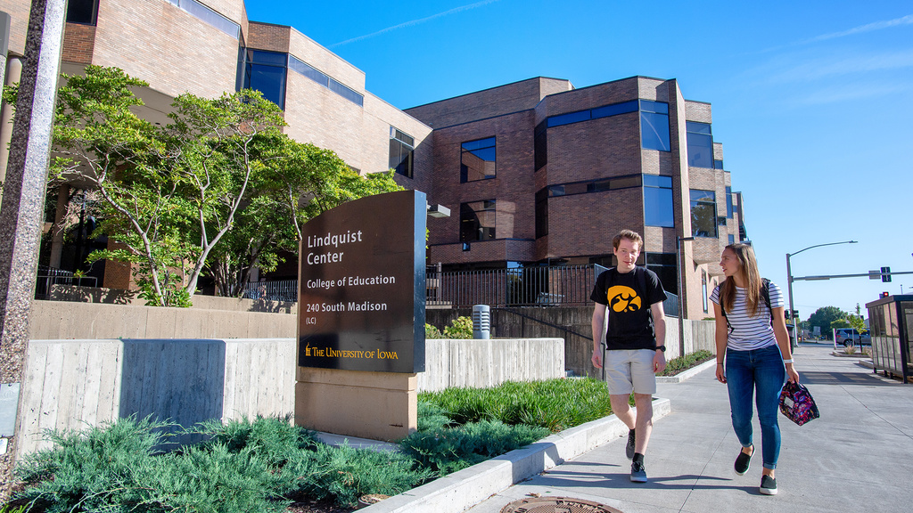 Two students walk along Lindquist Center on a sunny day. 