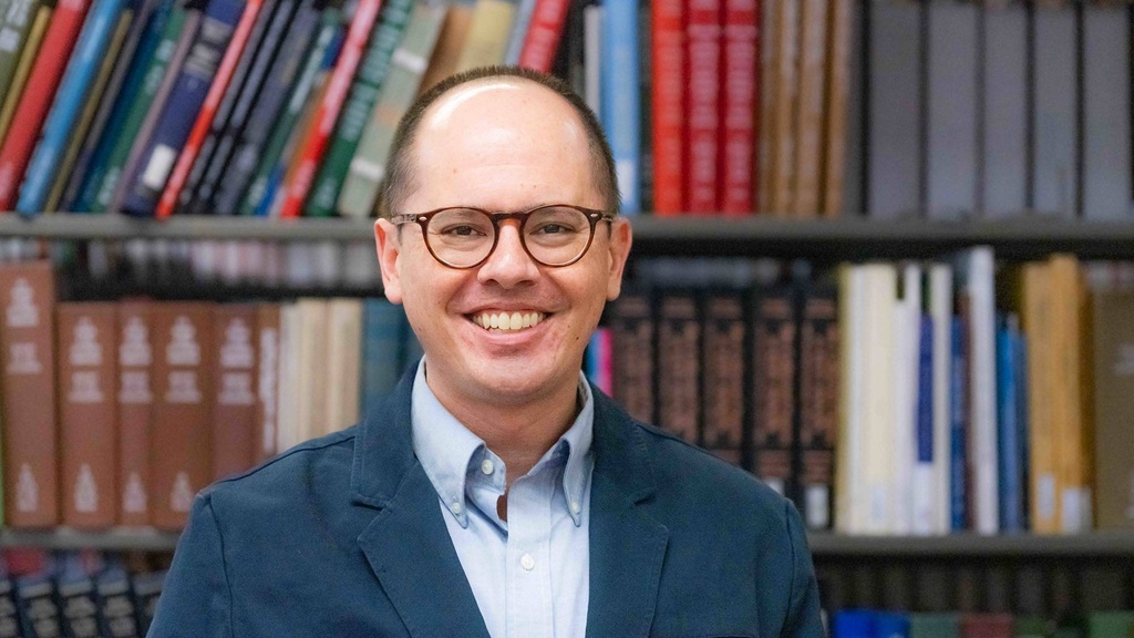 Shawn Datchuk stands in front of a bookcase
