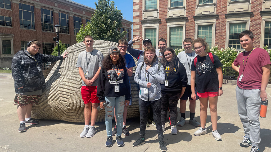 A group of students stand in front of the UI’s famous Brain Rock