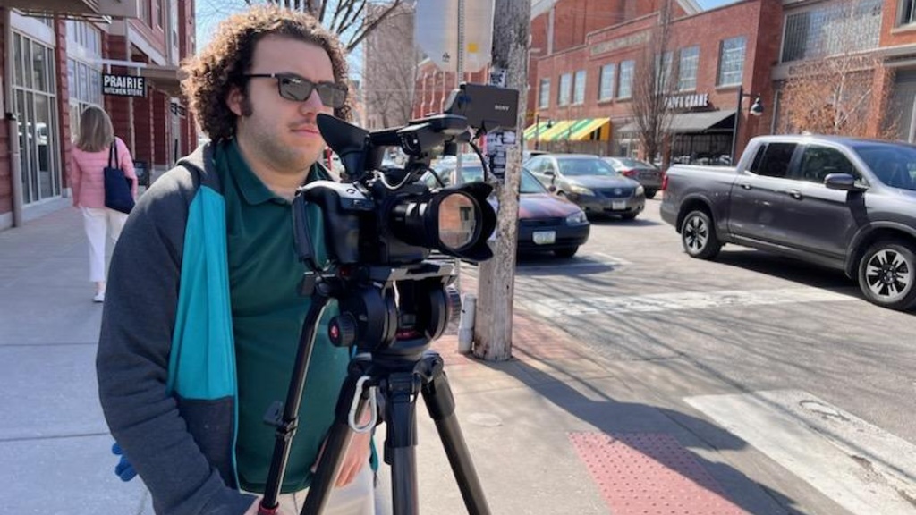 Alex Finch operates a video camera on an Iowa City sidewalk.