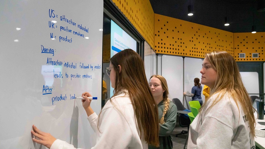 students writing on a white board during class