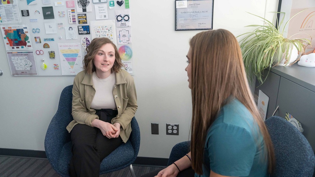 two women sit, talking