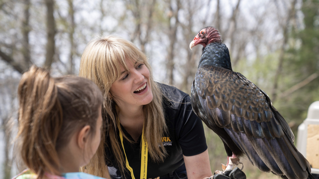 Woman smiles while holding raptor and showing little girl