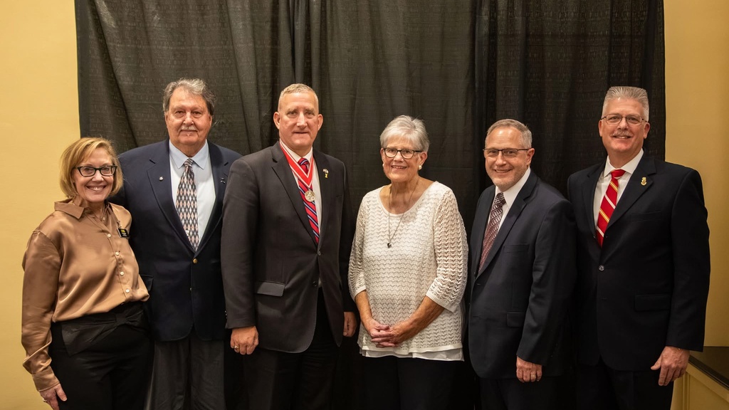 A group of alumni Veterans and University of Iowa staff pose in a group photo in the Iowa Memorial Union.