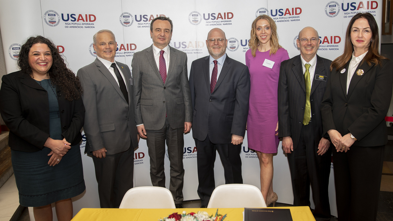 University of Iowa and Kosovo dignitaries pose for a group photo in front of a USAID backdrop to celebrate a new cooperative agreement launch.