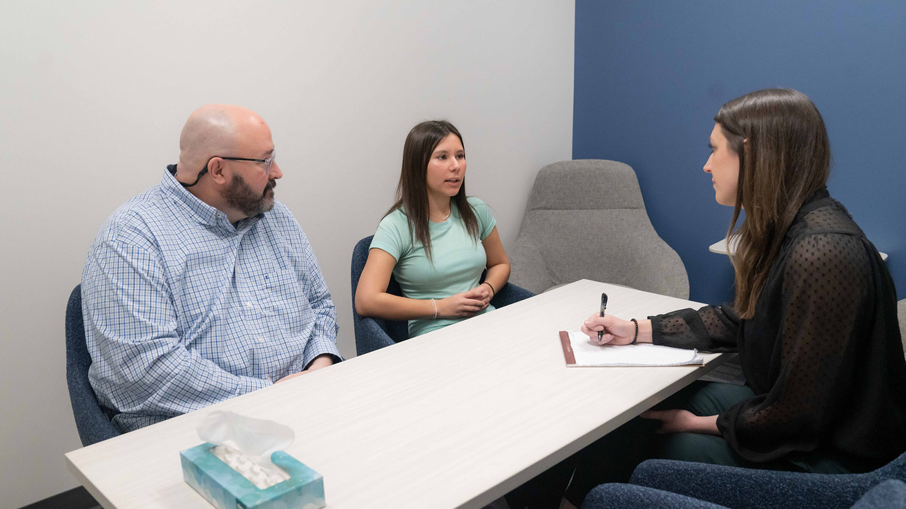 Taylor Ford, Scanlan Center’s assistant director of clinical services, talks to a man and young woman